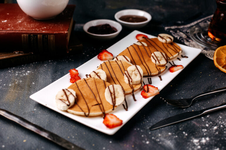 front-view-delicious-pancakes-along-with-red-strawberries-bananas-inside-white-plate-grey-surface